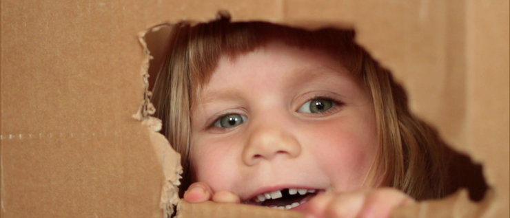 Mädchen schaut aus einem Loch im Karton I Ein Beitragsbild aus der Sachgeschichte: Lea und ihre Rakete