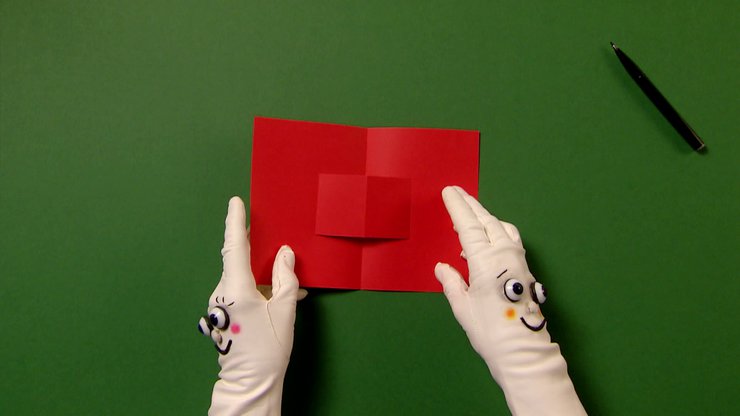 Zwei Hände mit Handschuhen klappen die rote Karten auf