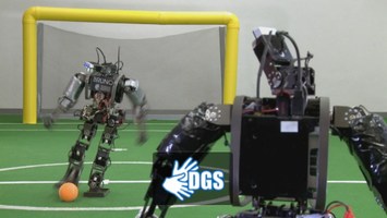 Roboter kicken auf dem Fußballfeld (mit DGS-Logo)