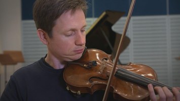 Johannes hï¿½lt einen Bogen und einer Geige spielbereit in der Hand