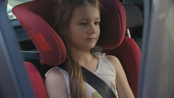 Mï¿½dchen sitzt in einem roten Kindersitz im Auto