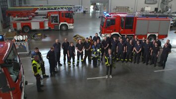 Feuerwehrmï¿½nner und -frauen in einer ï¿½bungshalle mit Laura