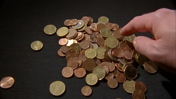 Hand zeigt auf einen Haufen Euro-Münzen