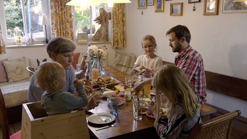 Familie mit 3 Kindern sitzt zu Hause beim Essen an einem Tisch