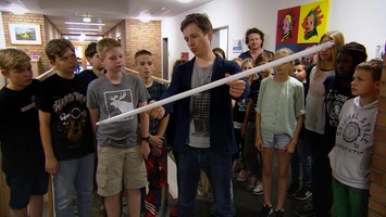 Johannes mit einer Neonröhe in der Hand vor einer Schulklasse