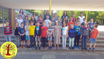Die vierte Klasse der GGS Keyenberg in Erkelenz steht vor ihrer Schule auf dem Schulhof.