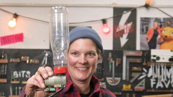 Laura mit einer leeren Plastikflasche in einer Werkstatt.