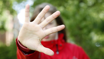 Mädchen mit abwehrender Hand vor dem Gesicht