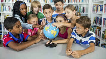 Eine Gruppe von Mädchen und Jungen schauen sich einen Globus an.