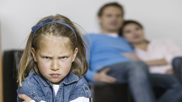 wütendes Mädchen mit Eltern im Hintergrund