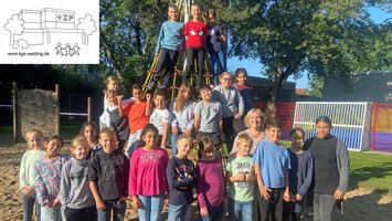 Eine Schulklasse steht zu einem Gruppenfoto versammelt vor einem Klettergerüst.