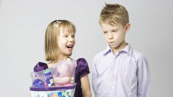 Ein Mädchen hält eine Schultüte in der Hand und ihr Bruder guckt neidisch.