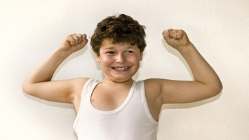 Ein Junge zeigt seine Muskeln wie ein starker Mann.