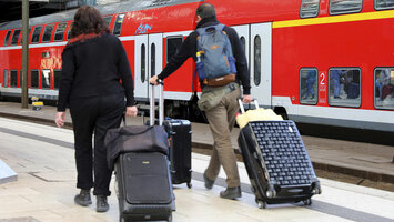 Zwei Reisende mit Koffern auf dem Bahnsteig