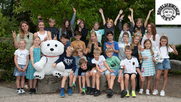 Eine Schulklasse mit einem Eisbär-Maskottchen steht zusammen.