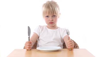 Mädchen, sauer, wartet vor leerem Teller aufs Essen