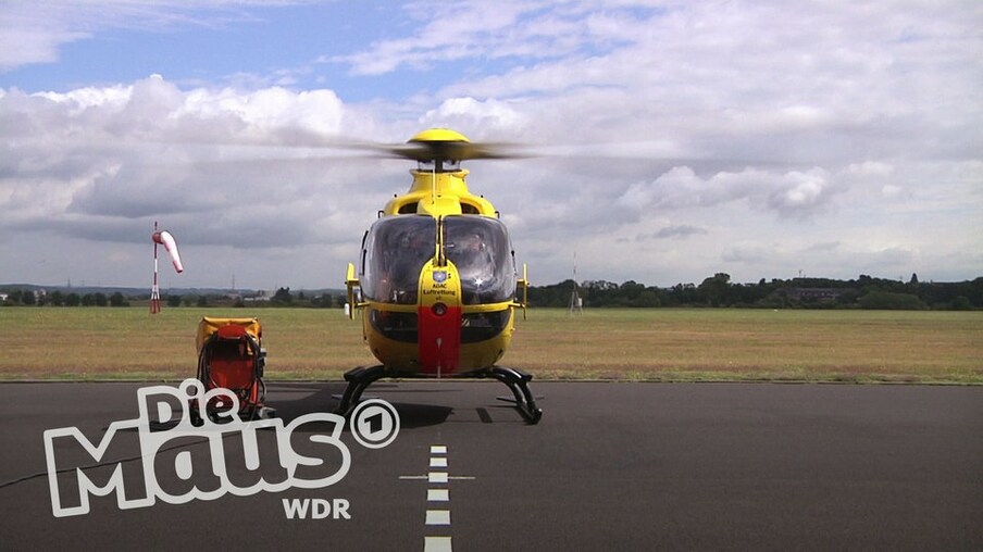 Ein gelber Hubschrauber steht auf einem Landeplatz. Die Rotorenblätter bewegen sich.