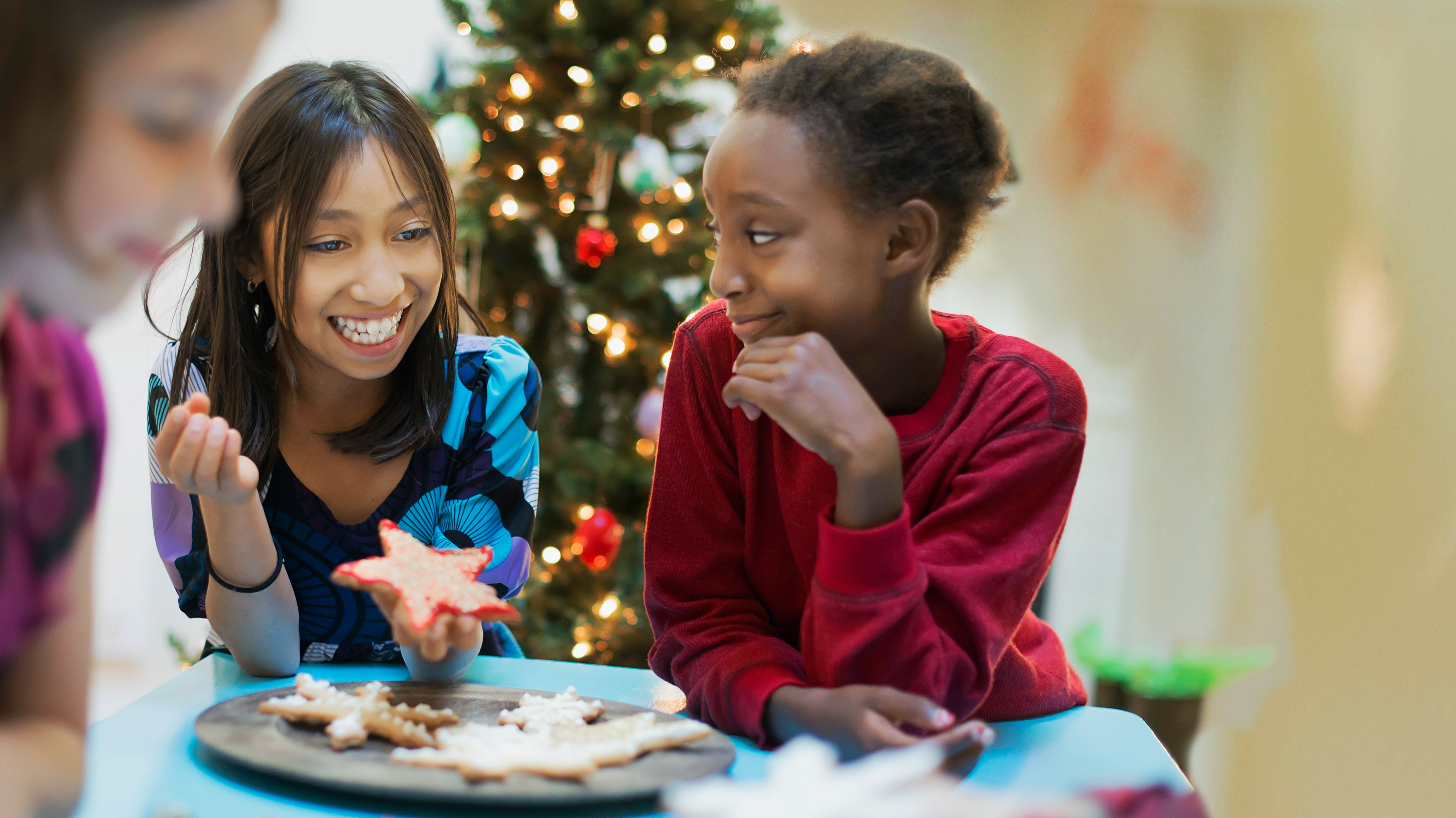 Bildrechte: picture alliance/Mint images Zwei Mädchen vor einem Weihnachtsbaum mit einer Schale Plätzchen
