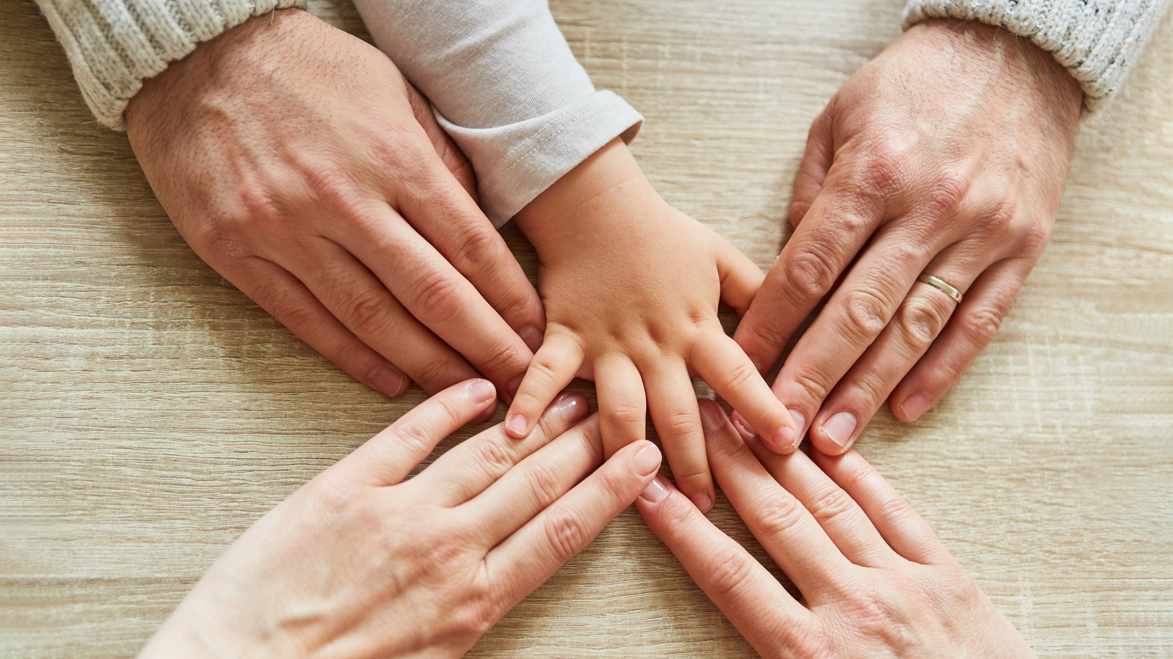 Hand von Kleinkind und Hände von Erwachsenen