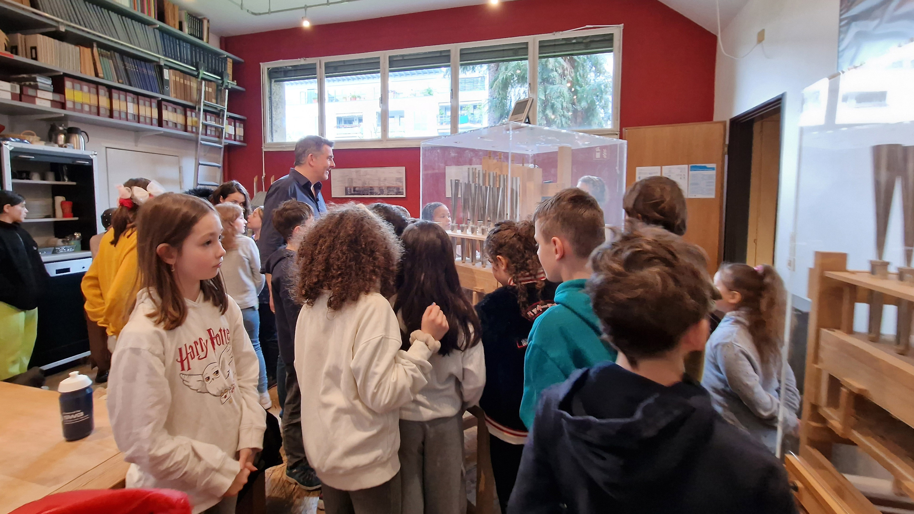 Kinder drängen sich vor einem Ausstellungskasten mit Orgelpfeifen