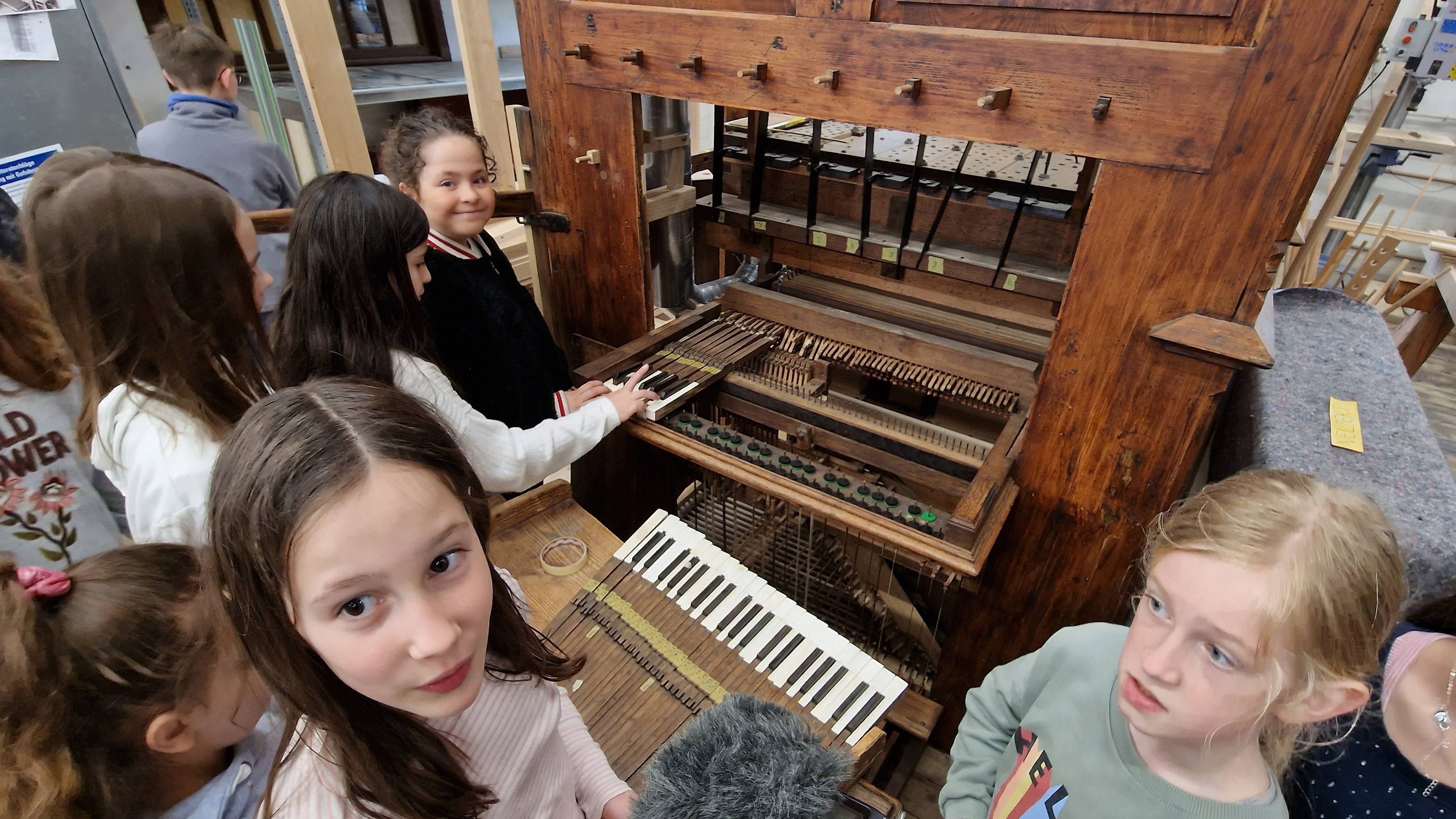 Kinder betrachten erstaunt eine alte Orgel