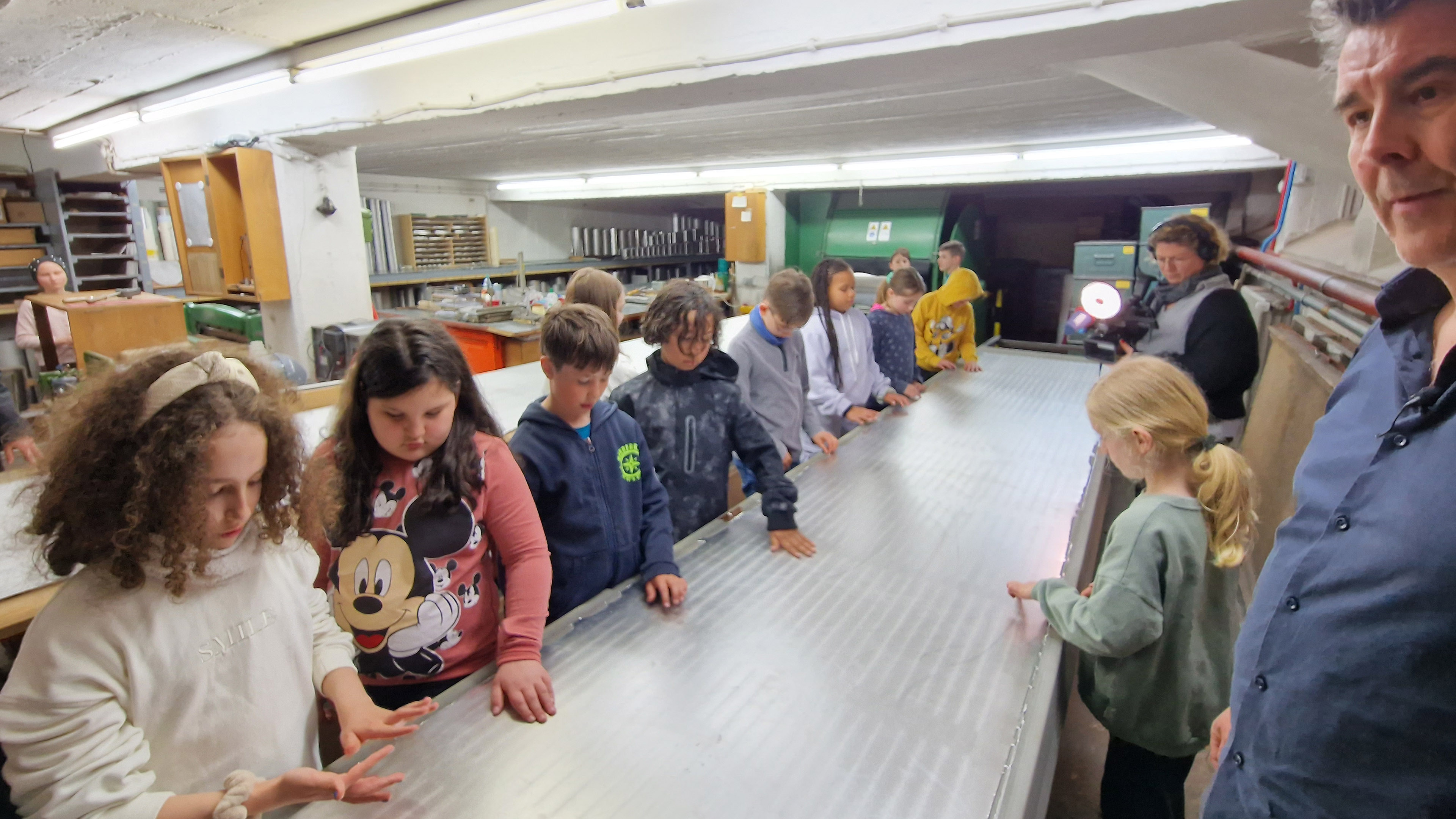 Kinder stehen an einem langen Werkstatt-Tisch