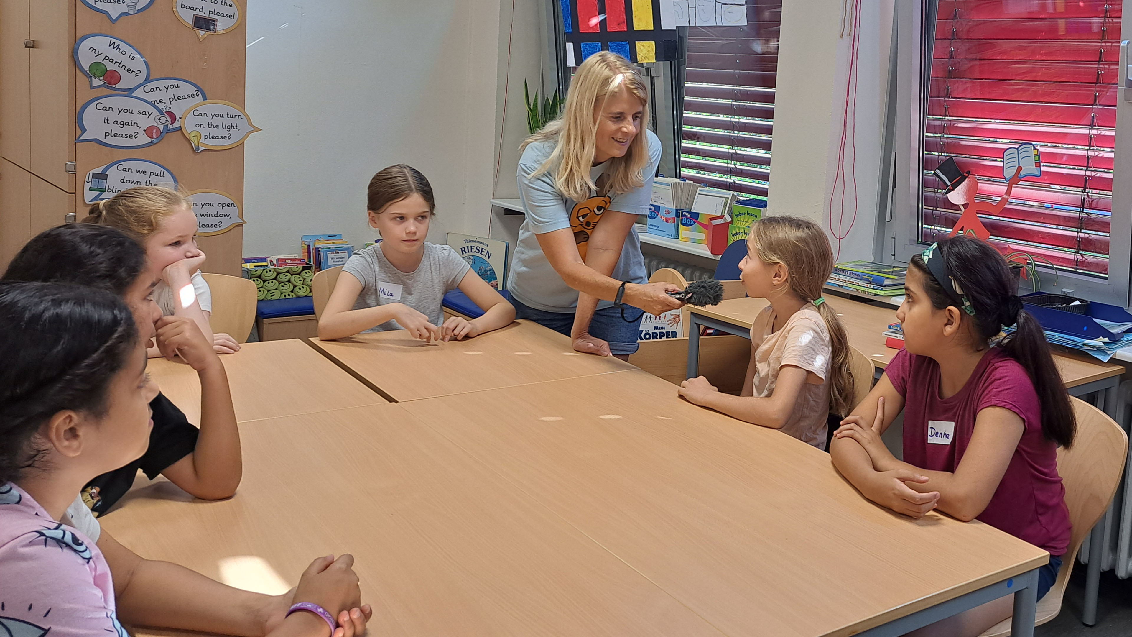 MausReporterin Christina interviewt Kinder der MausKlasse im Klassenzimmer mit einem Mikrofon