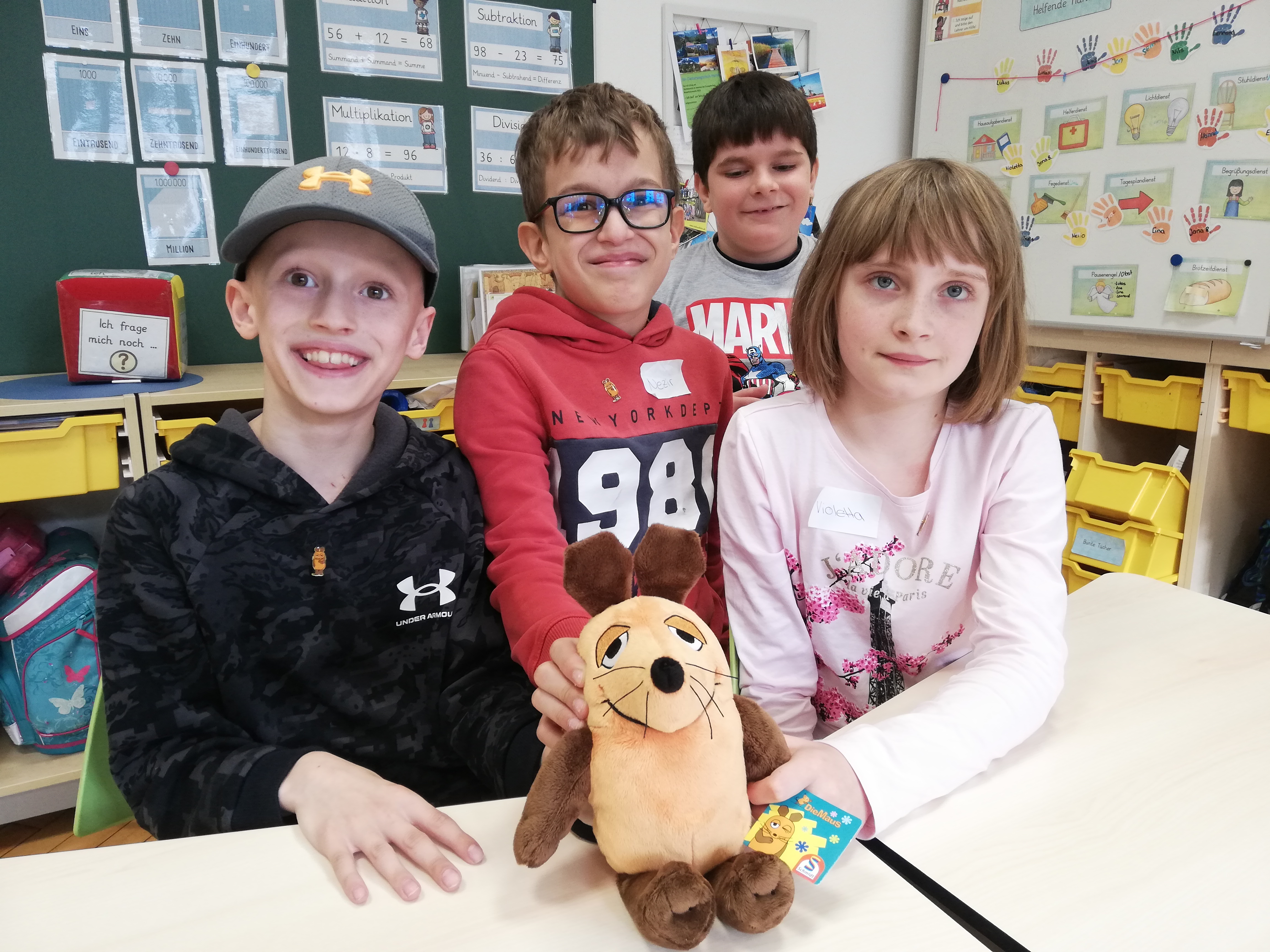 Vier Kinder halten eine Stoff-Maus in der Hand.