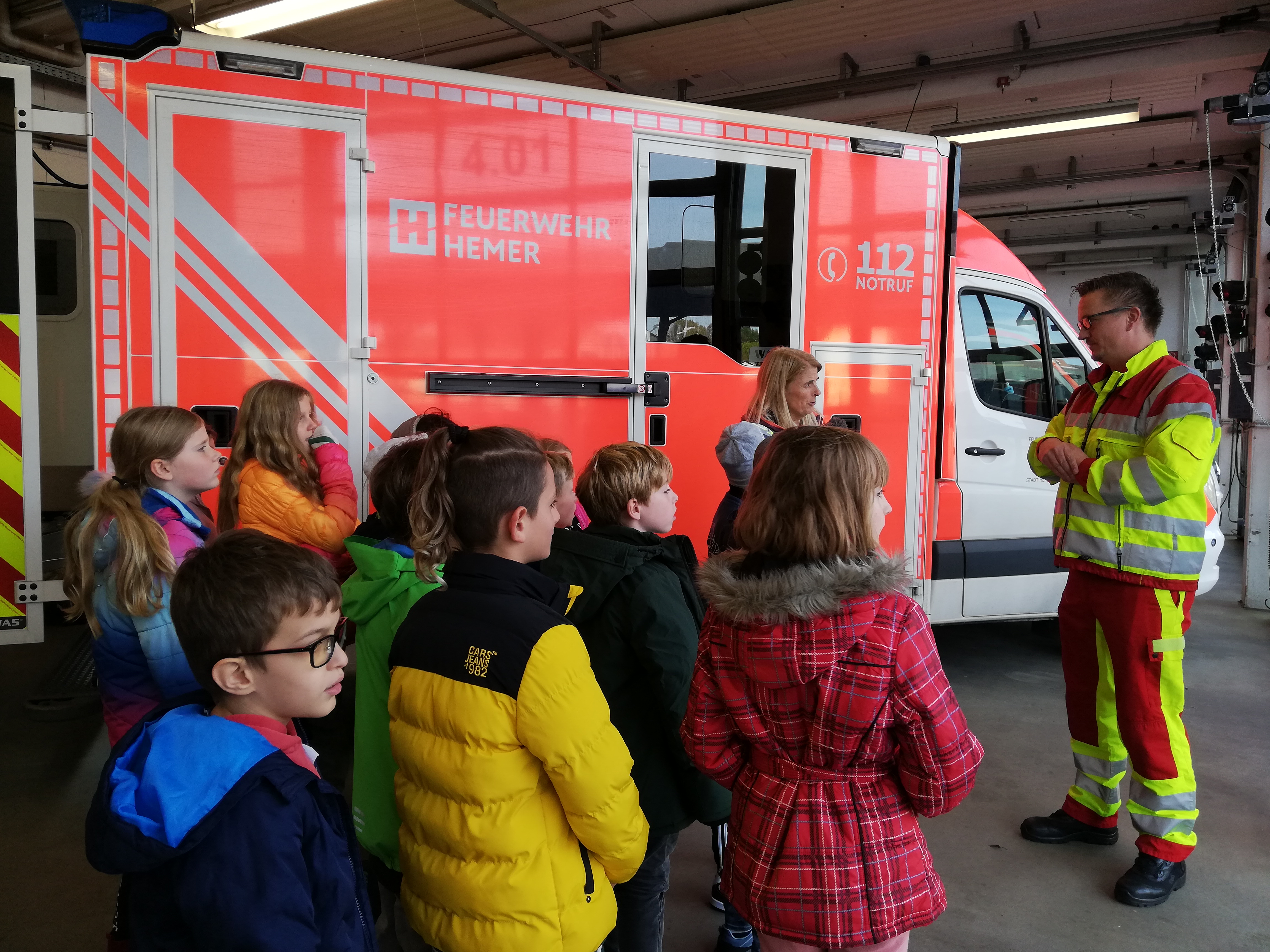 Eine Schulklasse steht vor einem Rettungswagen.