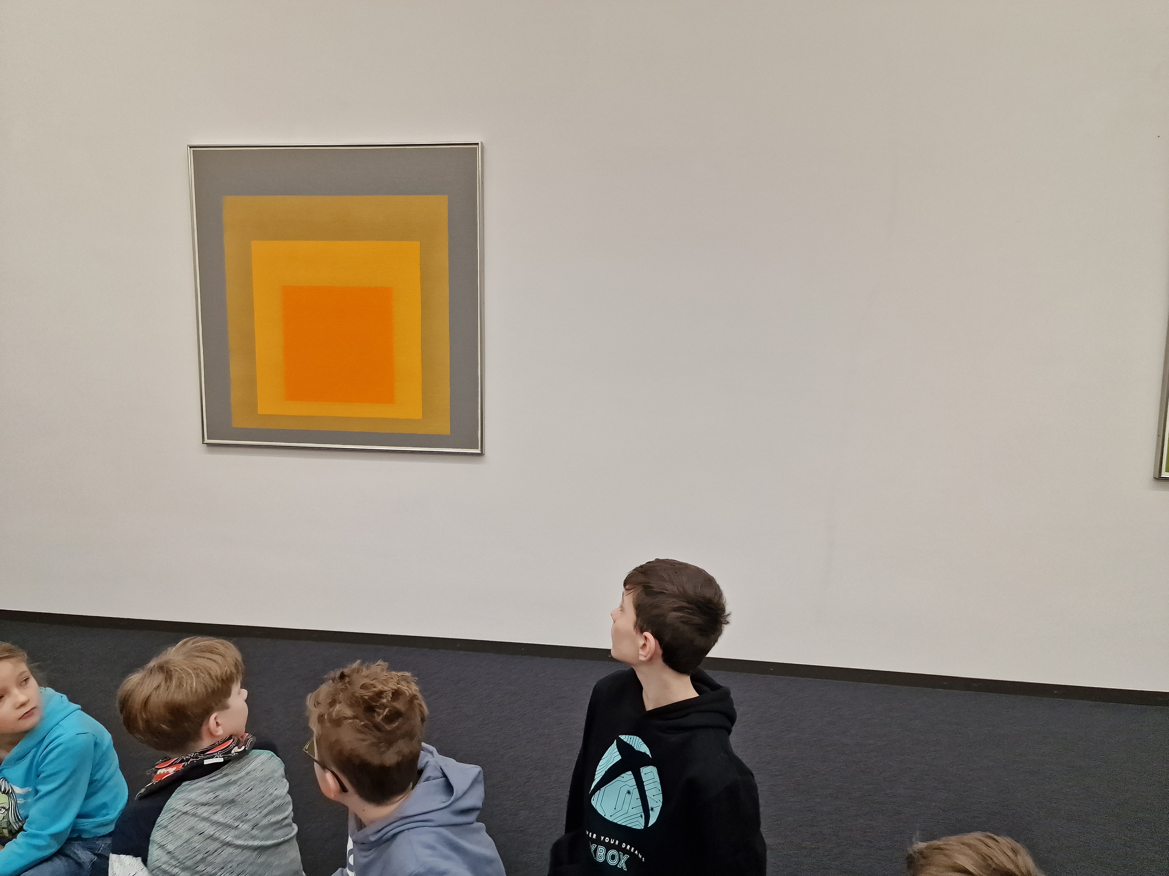 Ein Junge schaut auf ein orangefarbenes Quadrat