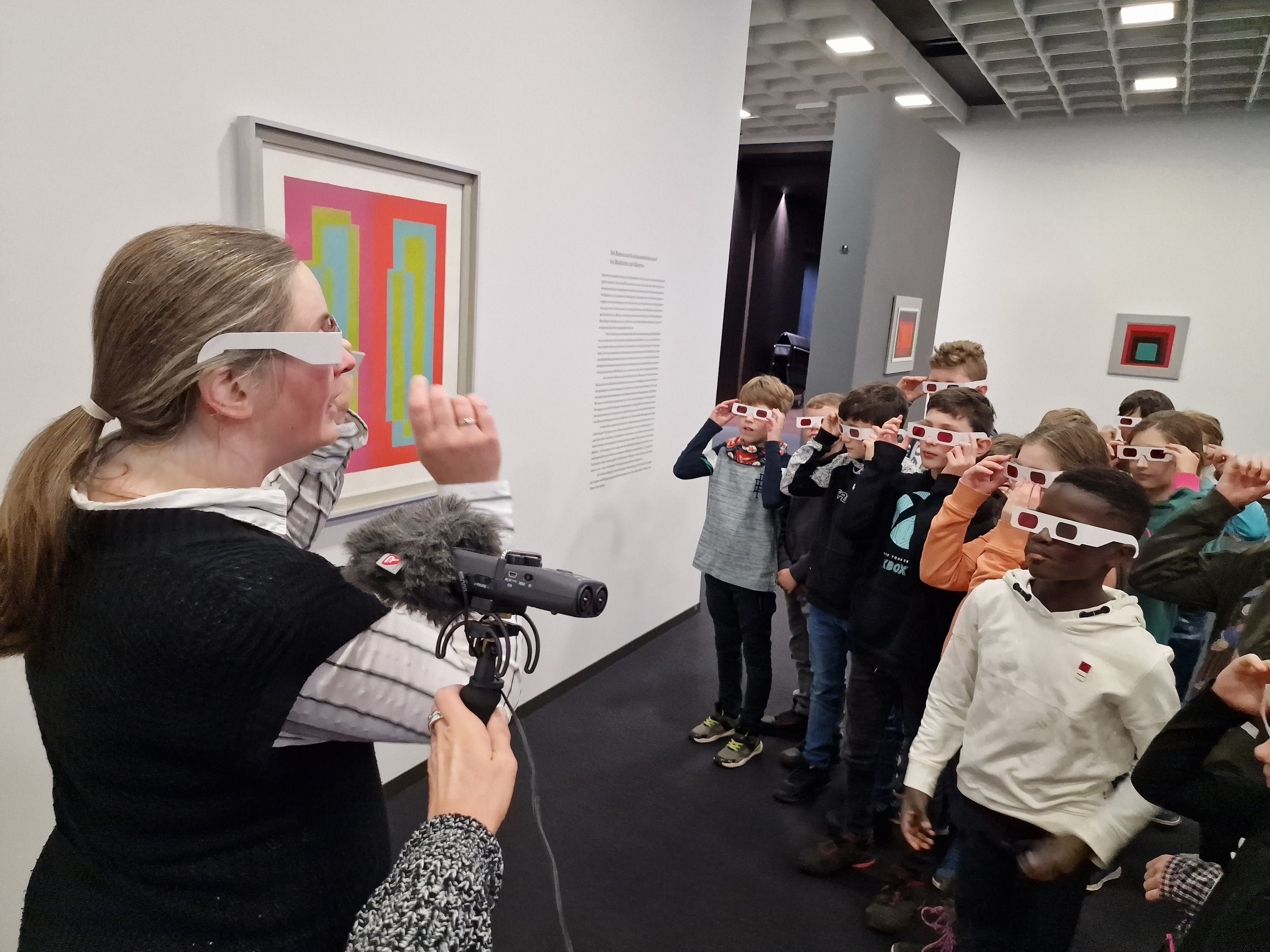 Eine Gruppe von Schülerinnen und Schülern steht mit Brillen in einem Museum