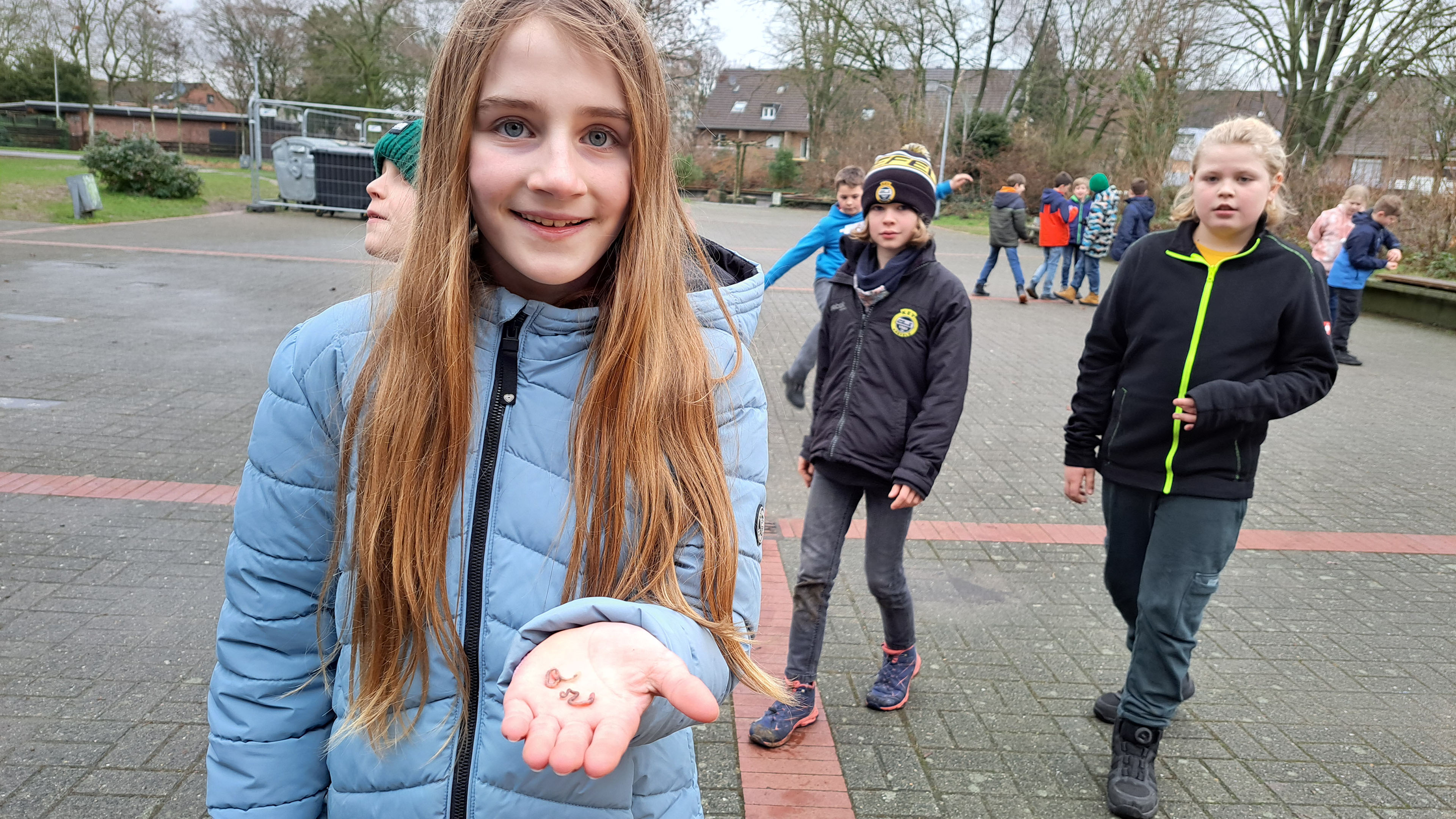 Mädchen zeigt einen Regenwurm in die Kamera 