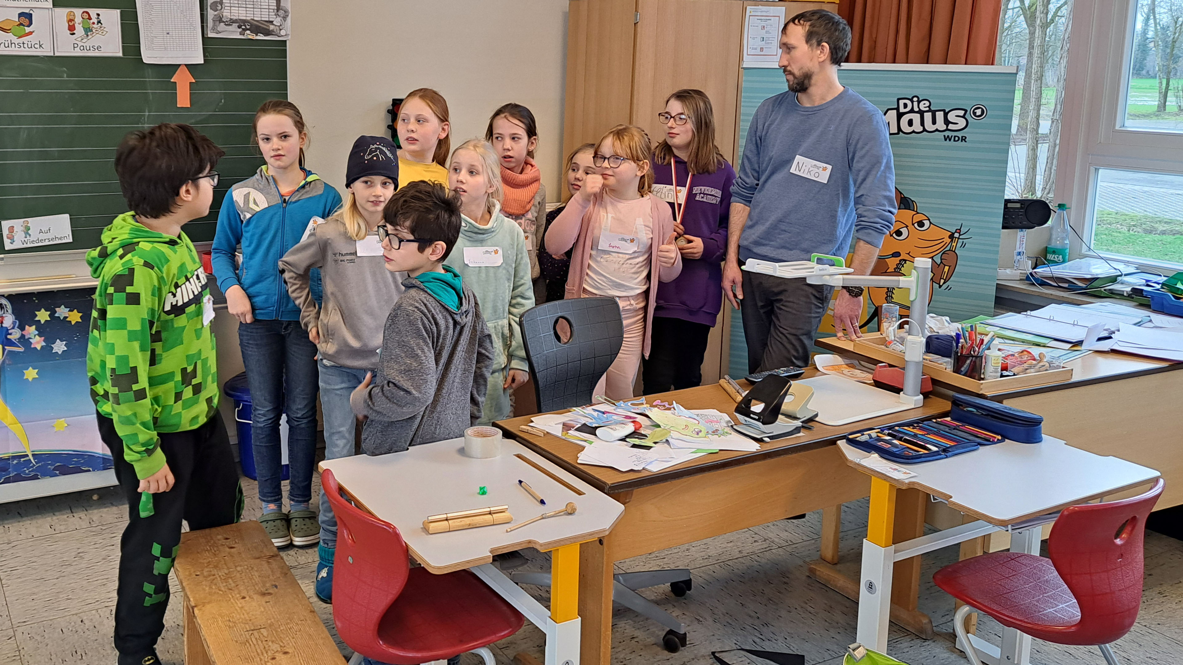 Eine Gruppe von Kindern steht mit einem Mann zusammen und berät sich.