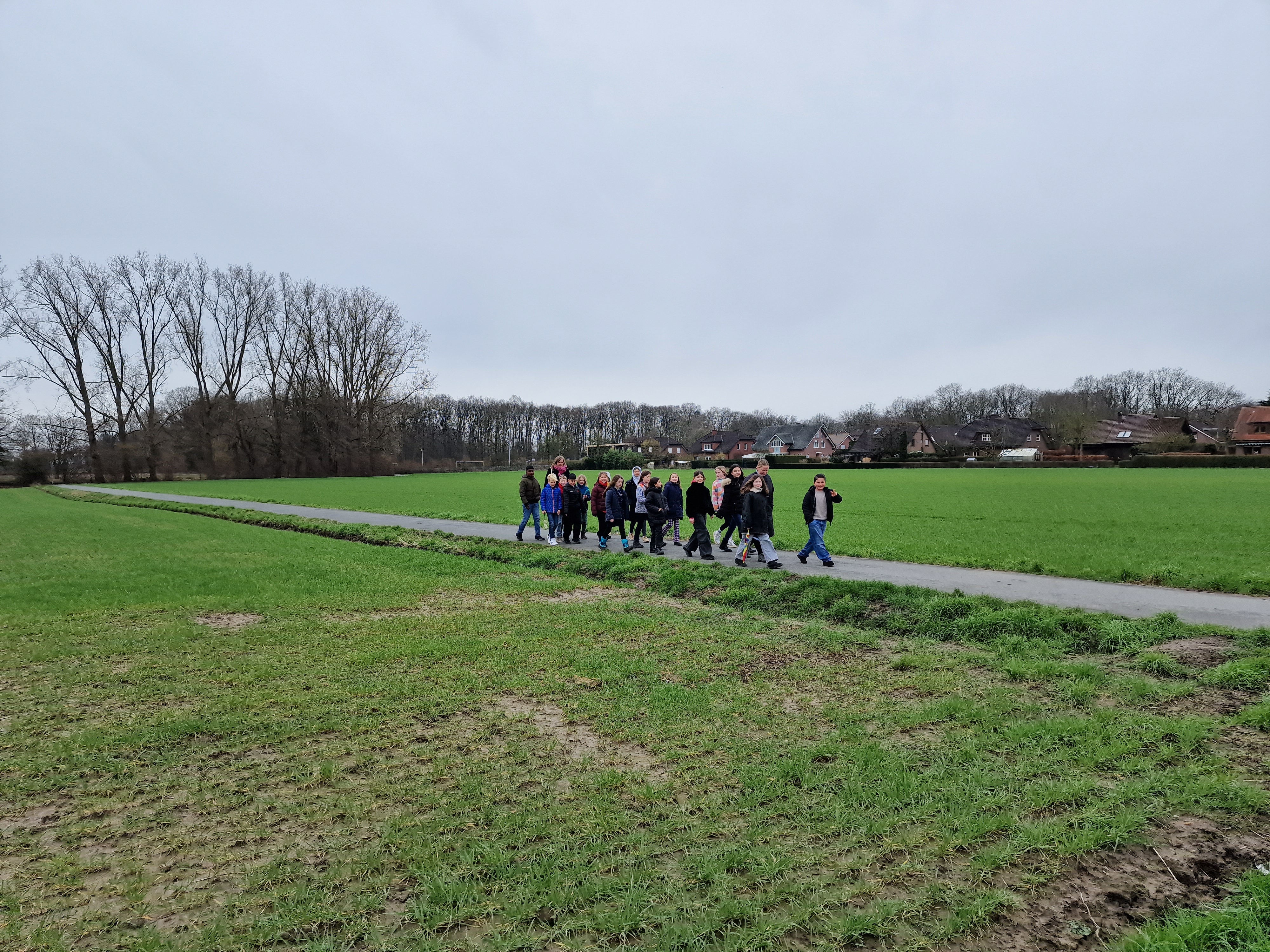 Eine Gruppe von ungefähr 20 Kindern geht auf einem Feld spazieren.