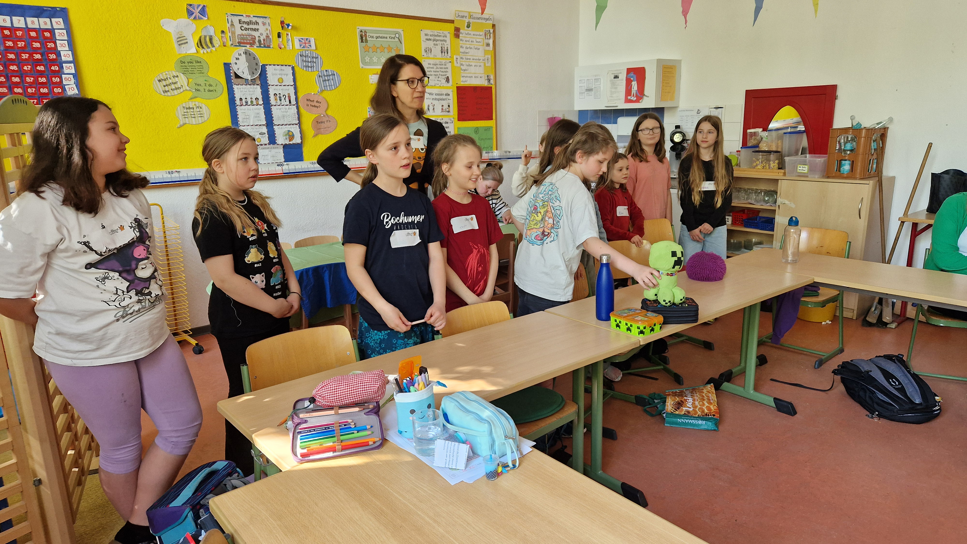 Kinder der MausKlasse stehen an den Tischen im Klassenzimmer