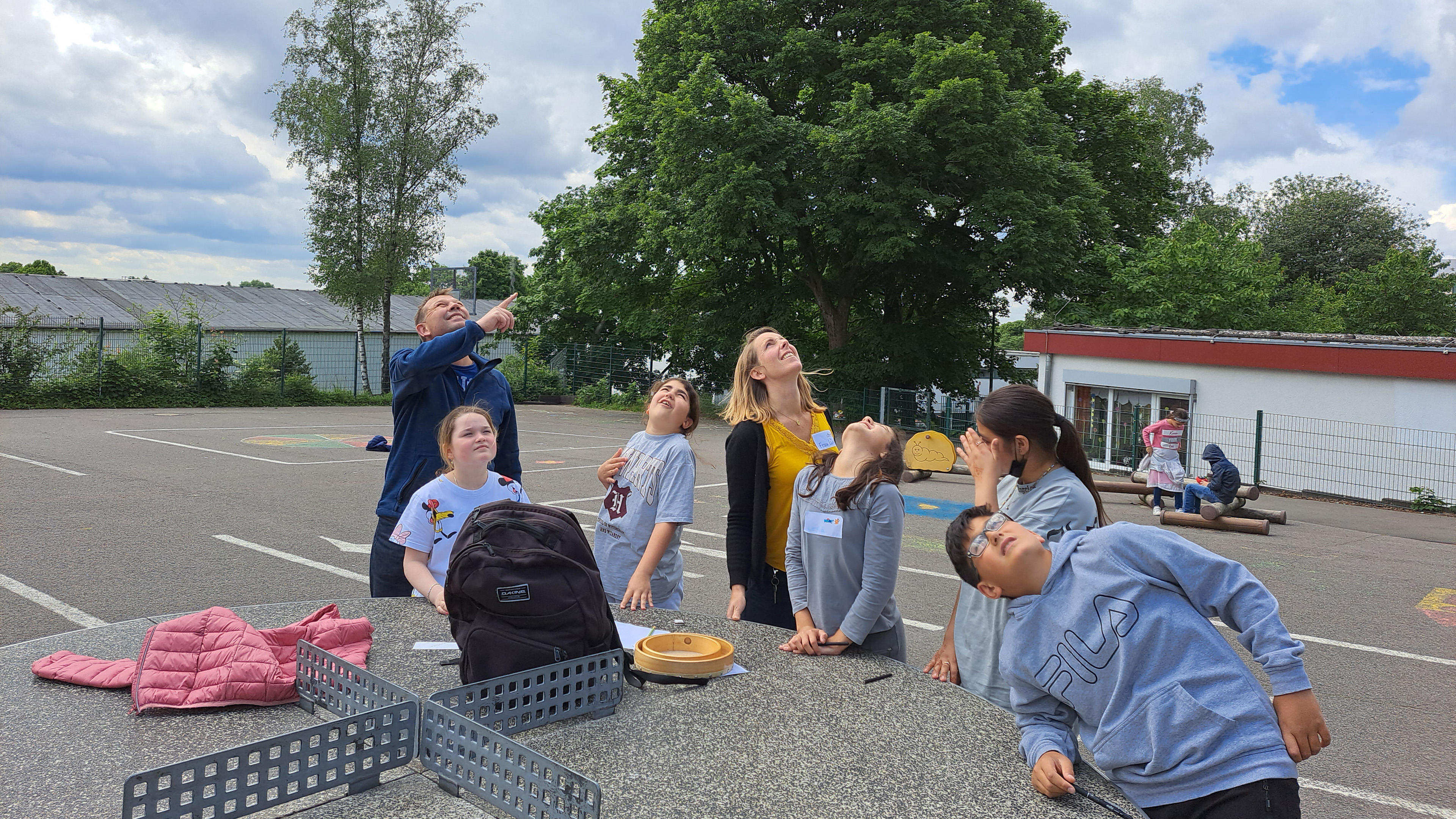 Eine Gruppe von Kindern und Lehrern guckt in den Himmel