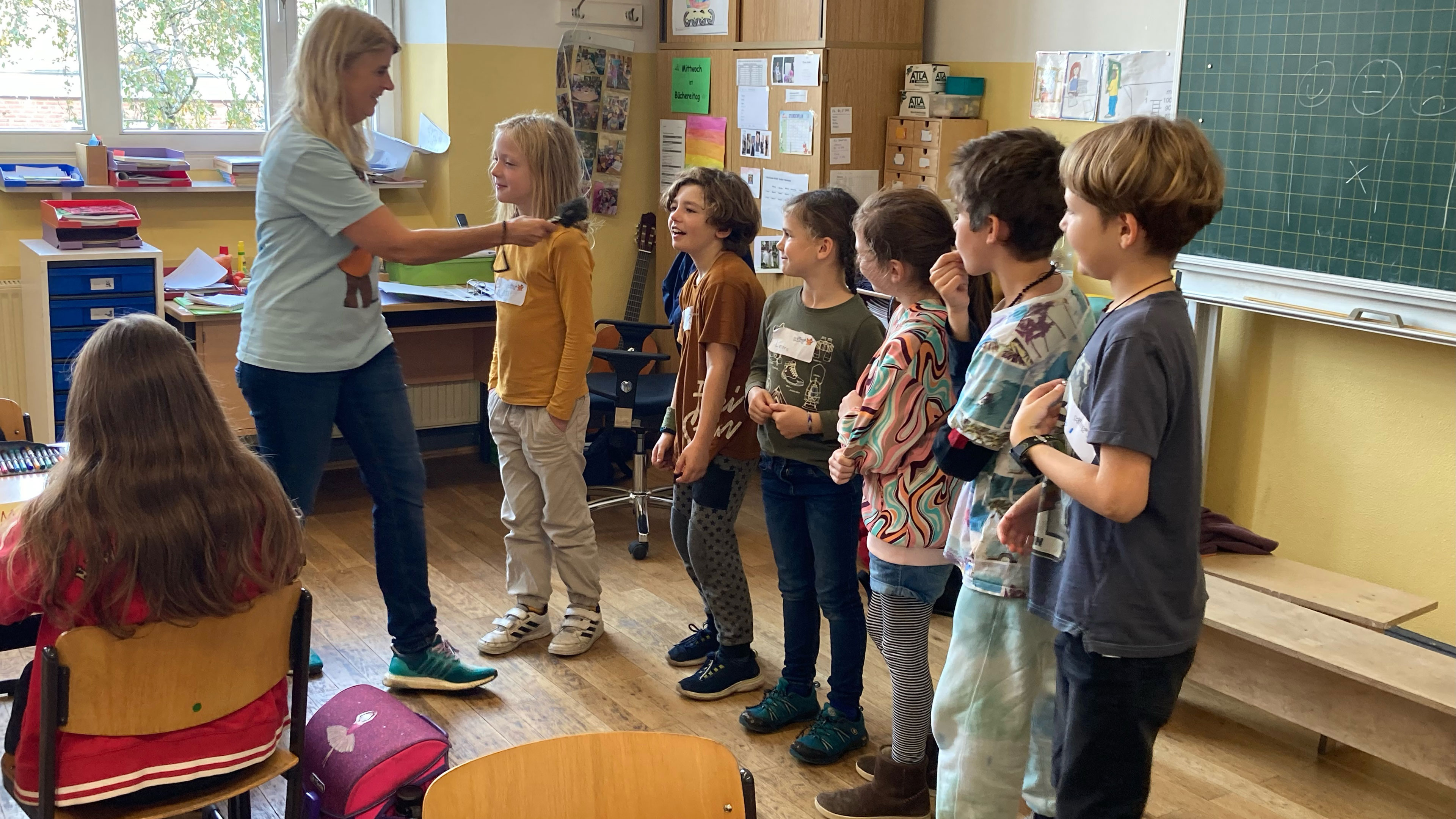 Eine Gruppe von Kindern steht nebeneinander in einem Klassenraum.