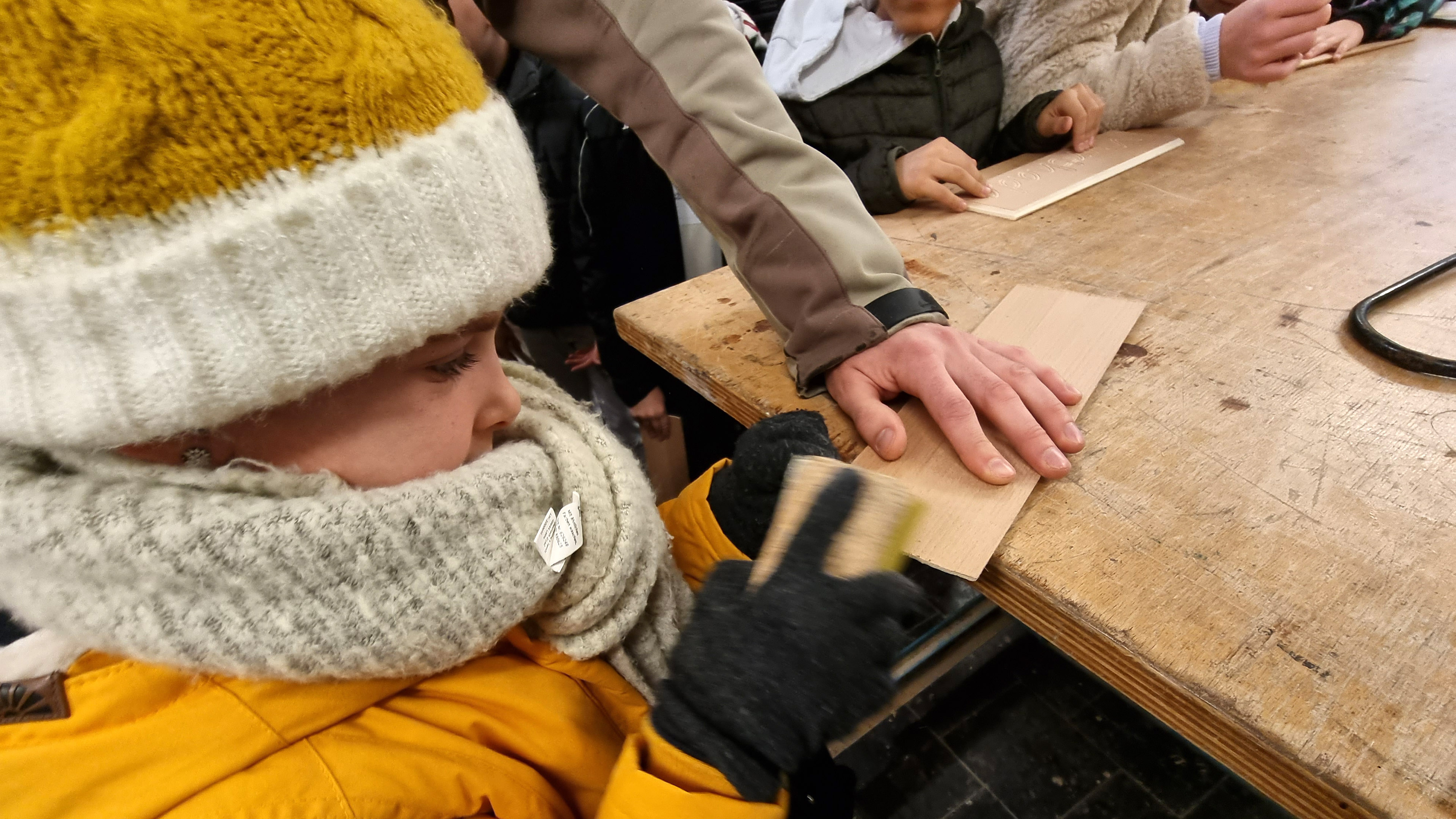 Ein Mädchen schleift ein Holzstück ab