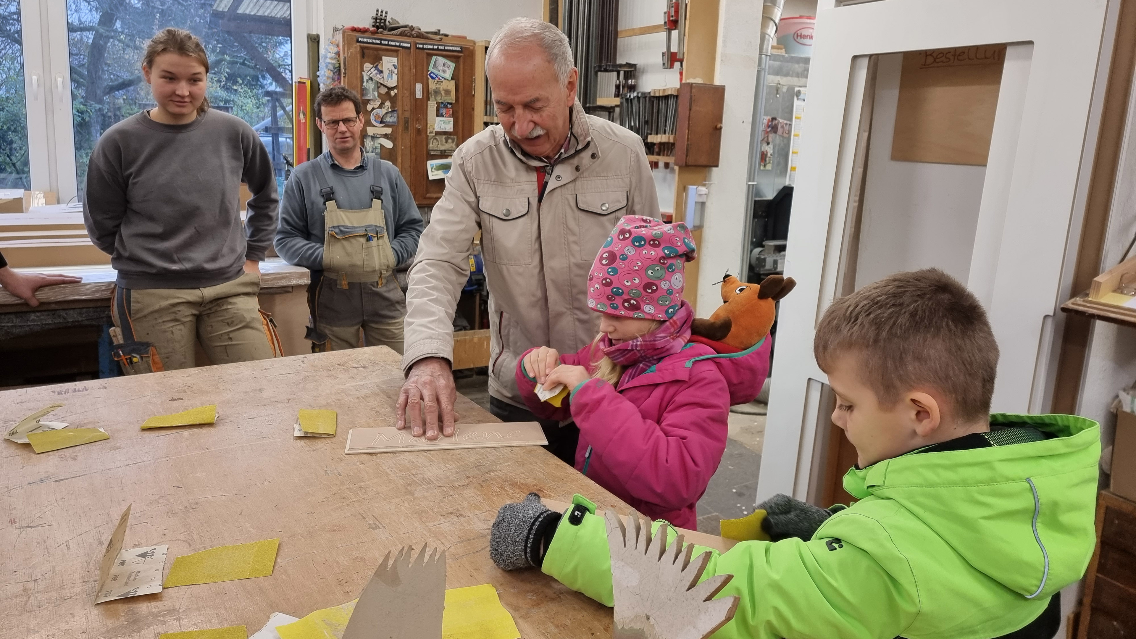 Senior-Chef Josef Schneider hilft Kindern beim Holz abschleifen
