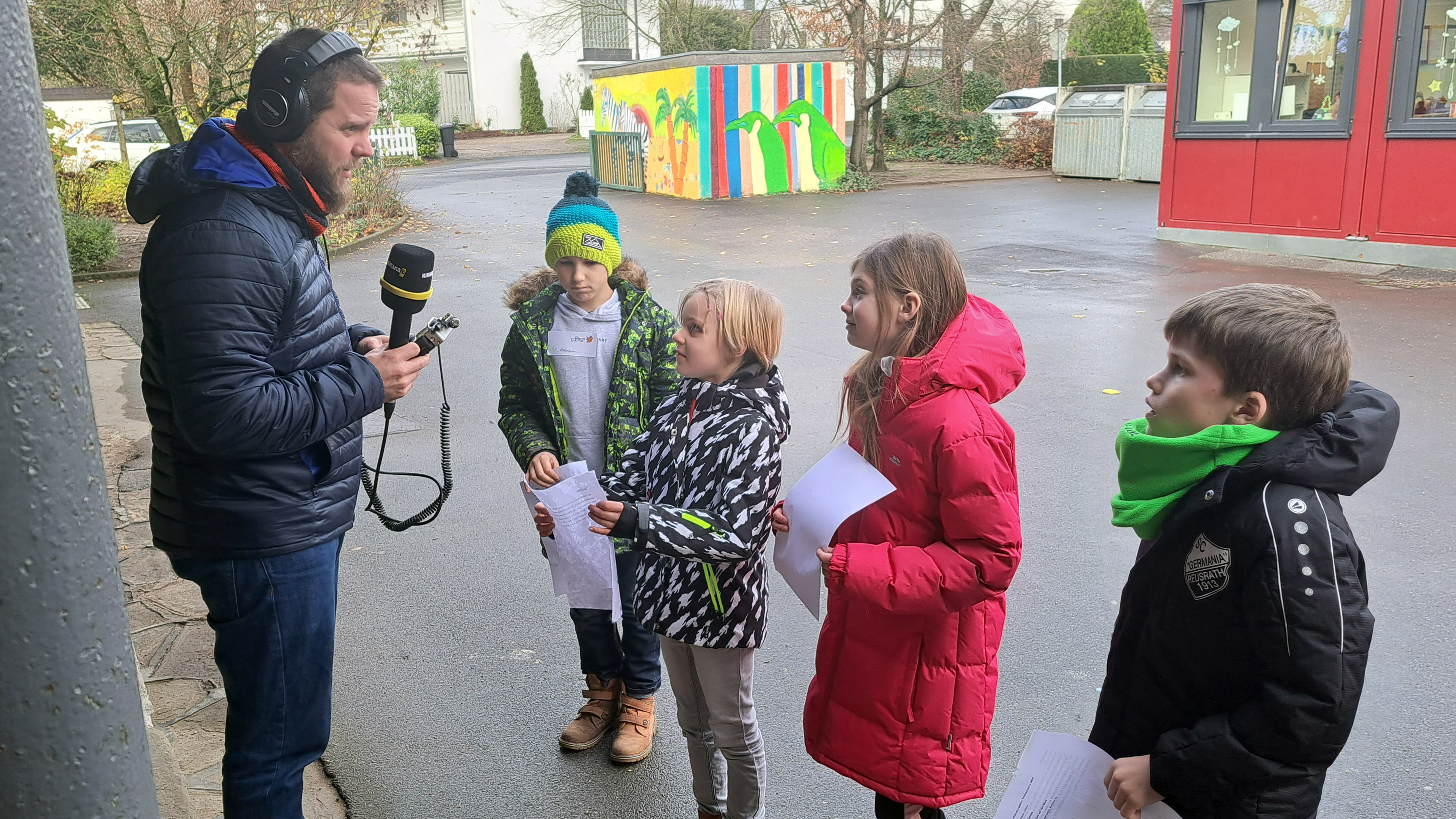 MausReporter Sebastian hält einer Gruppe Kinder ein Mikrofon unter die Nase