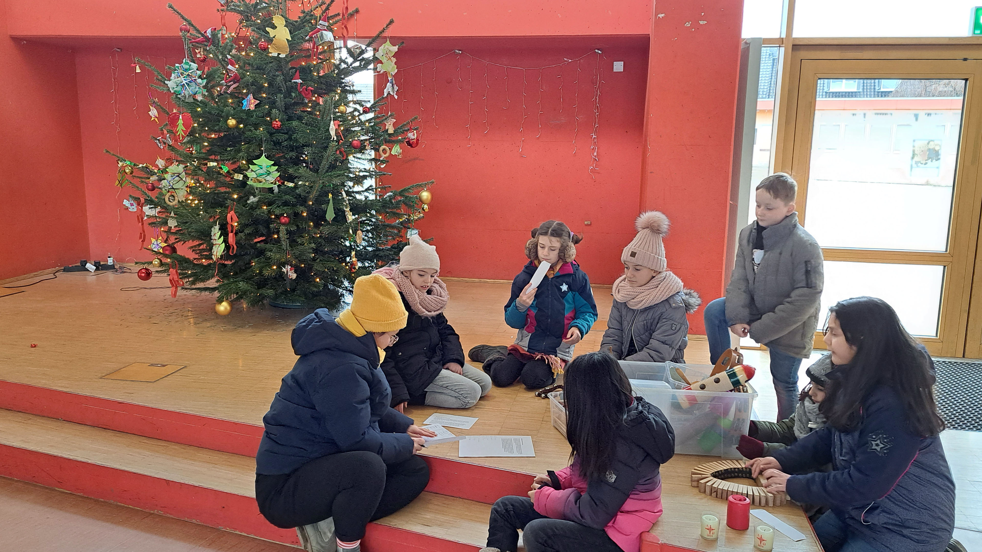 Kinder sitzen vor einem Weihnachtsbaum