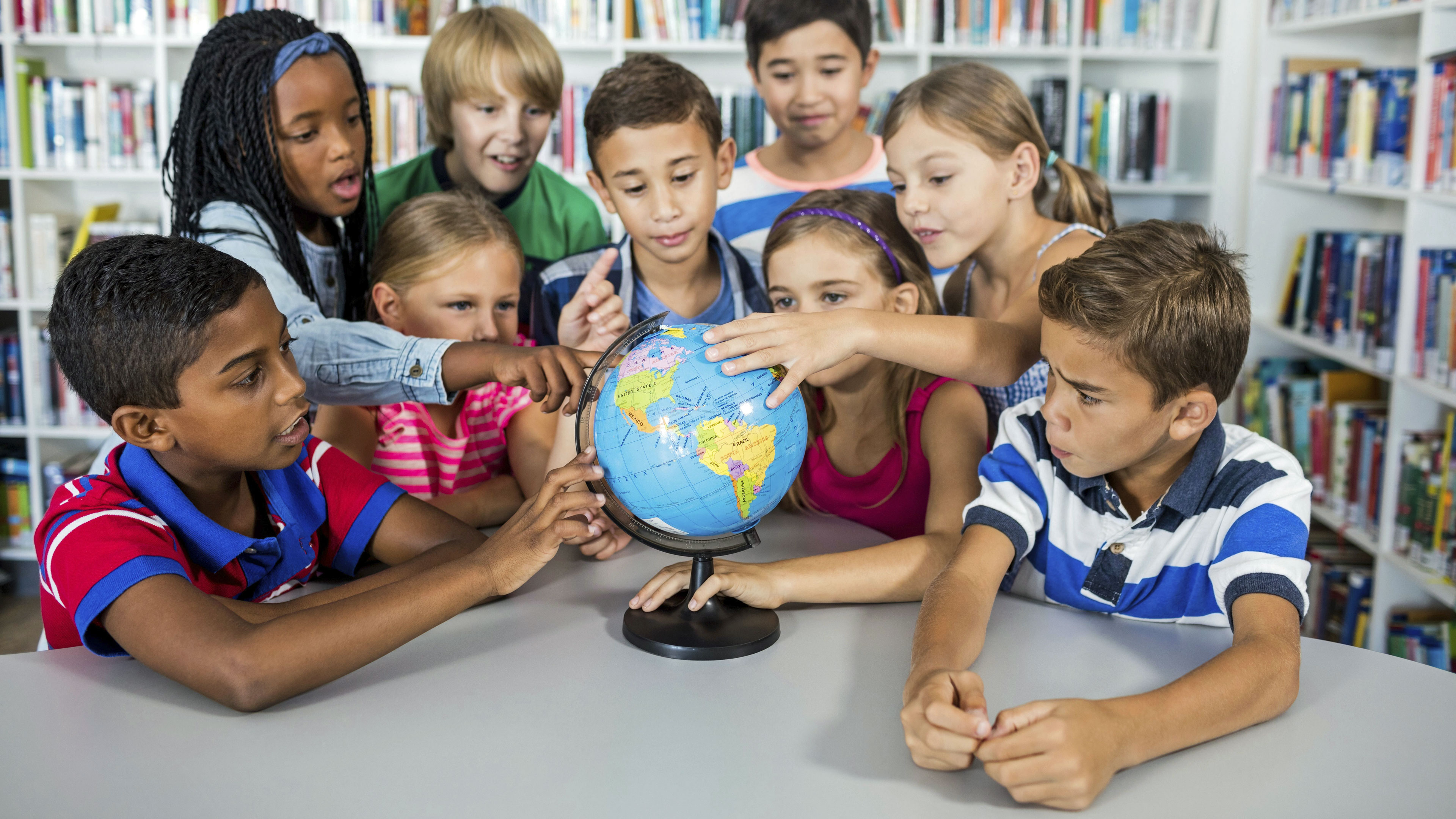 Eine Gruppe von Mädchen und Jungen schauen sich einen Globus an.