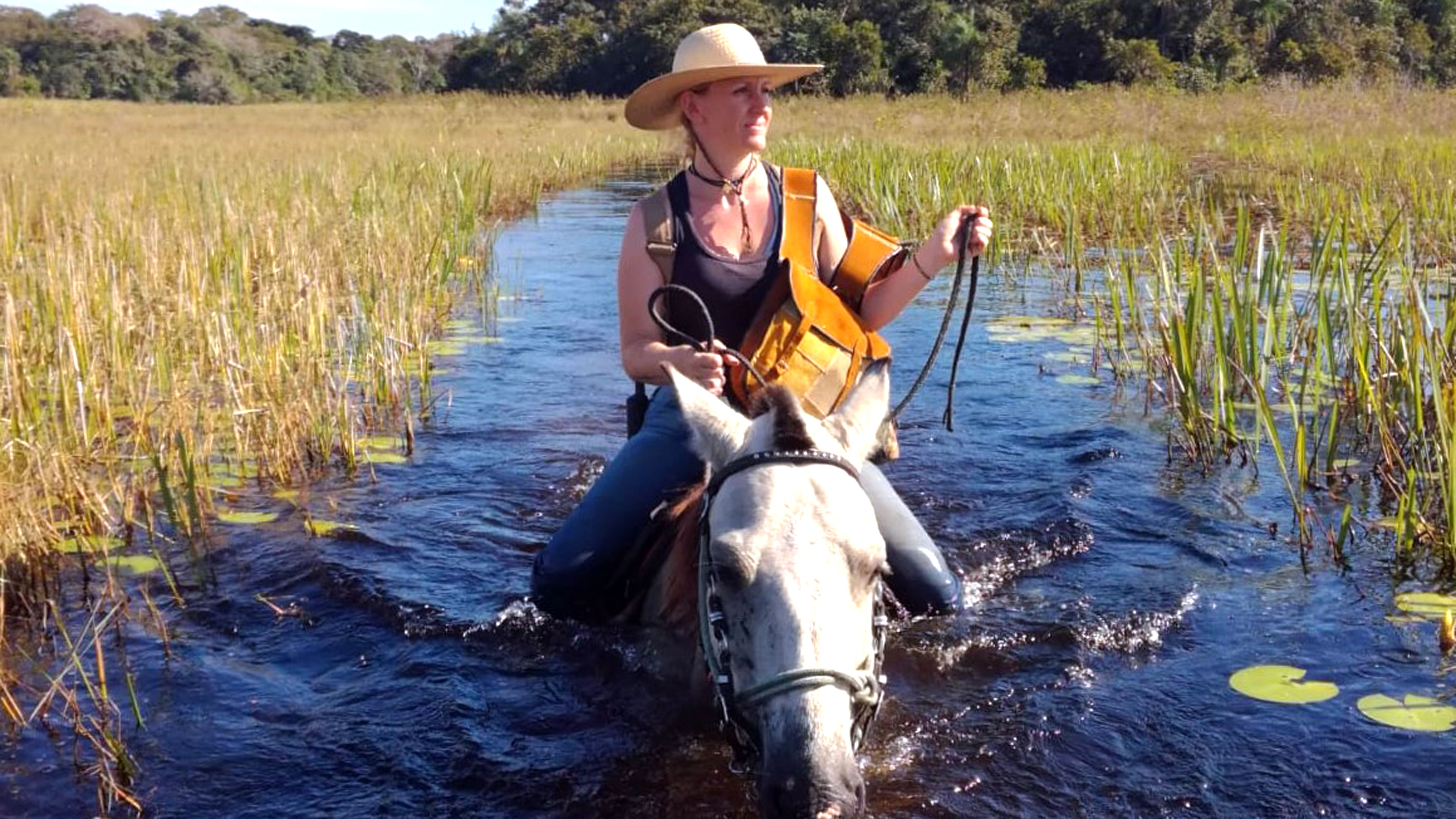 Lydia reitet auf einem Pferd durch den Fluss
