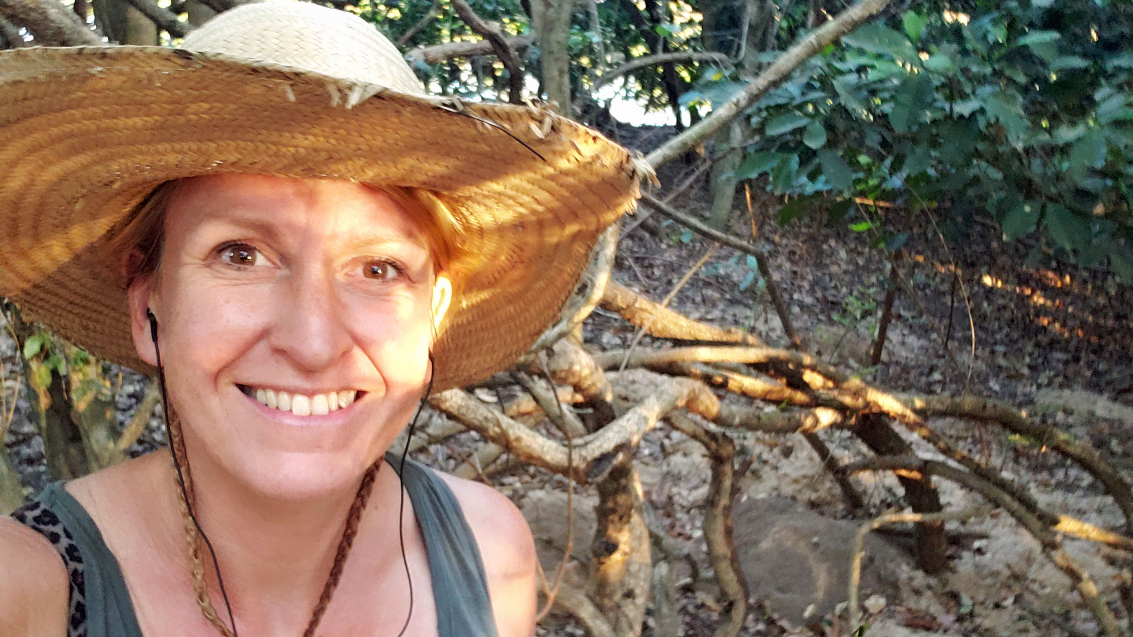 Eine Forscherin mit Hut in einem Waldstück