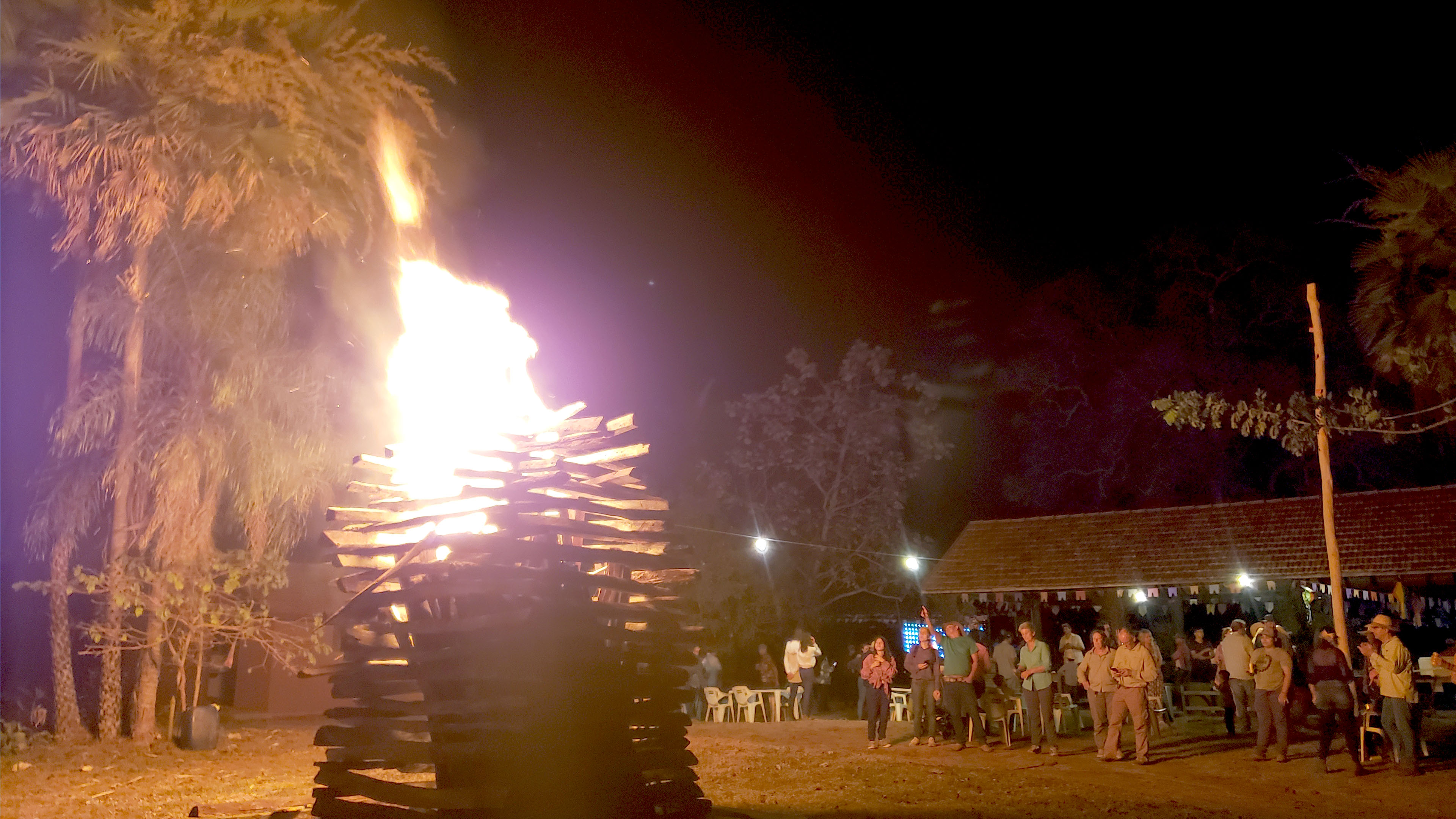 Menschengruppe am Lagerfeuer vor nächtlichem Himmel
