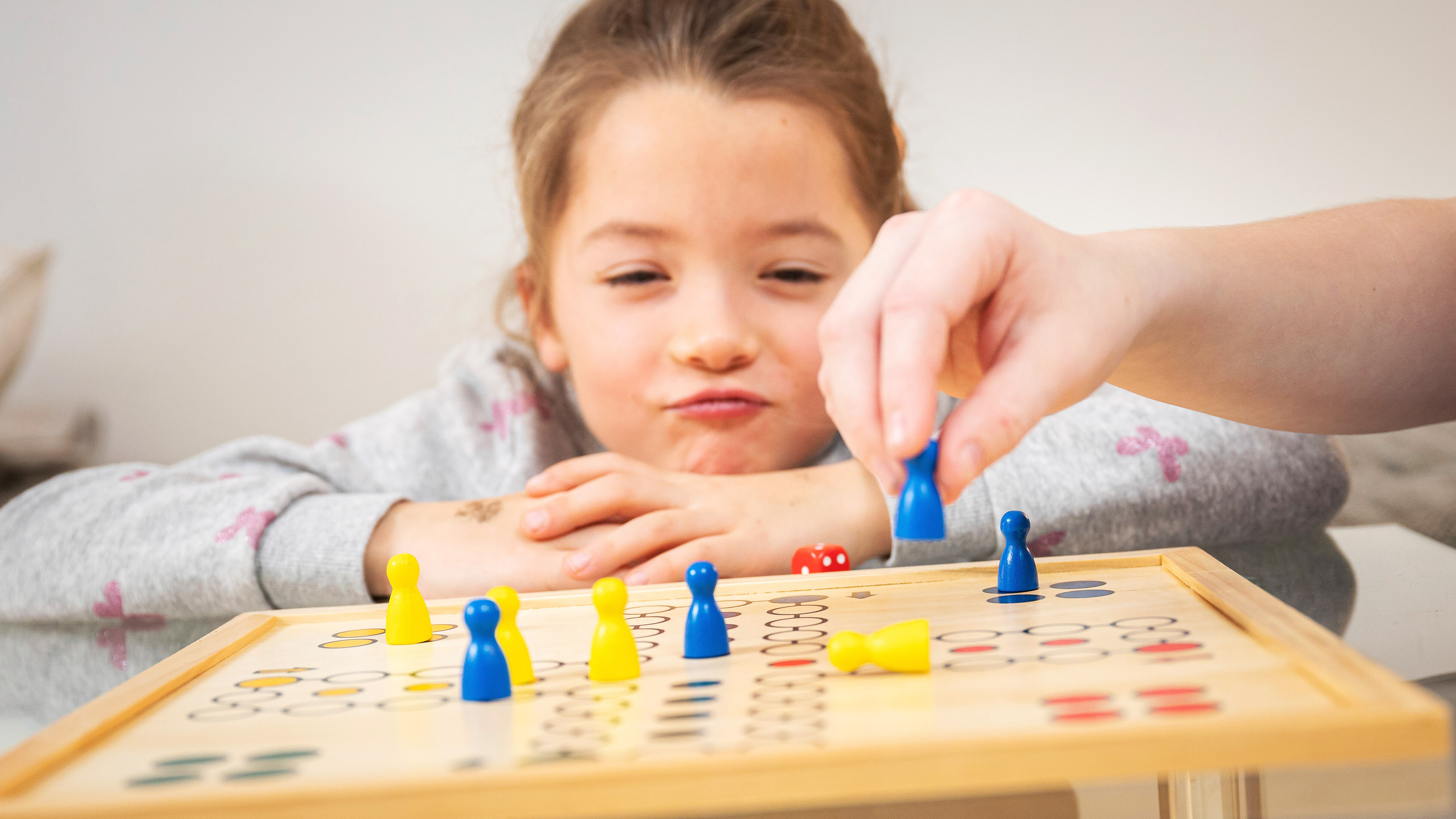 Junge bewegt eine Spielfigur auf einem Spielbrett