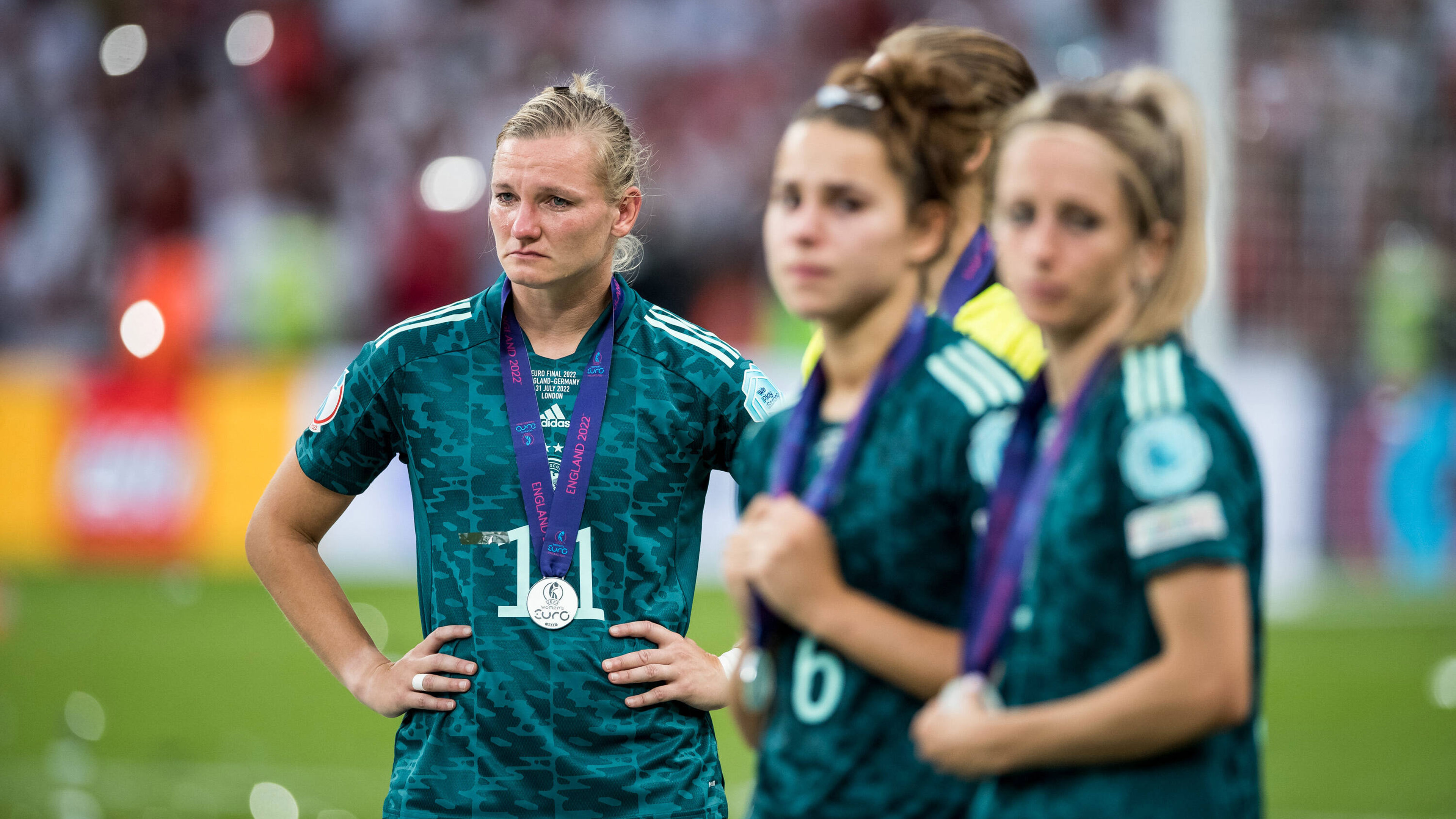 Drei Fußballerinnen stehen auf dem Platz und weinen.
