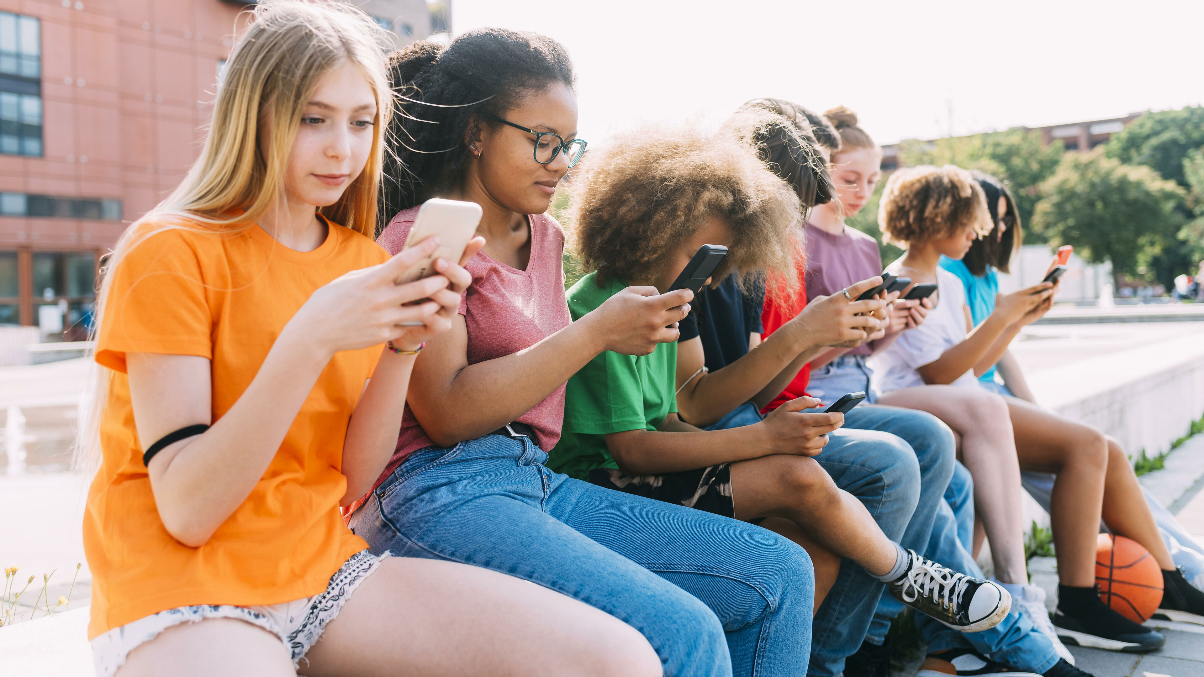 Eine Gruppe von Jugendlichen sitzt zusammen und schaut auf ihre Smartphones.