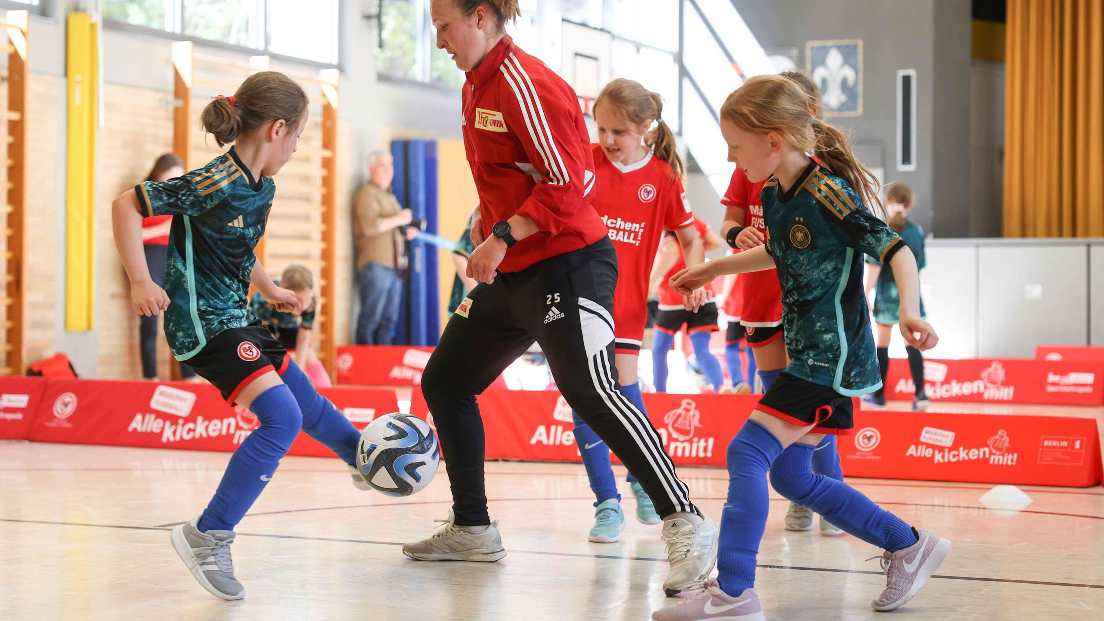 Bei einem Fußballtraining in einer Halle spielen Mädchen Fußball.