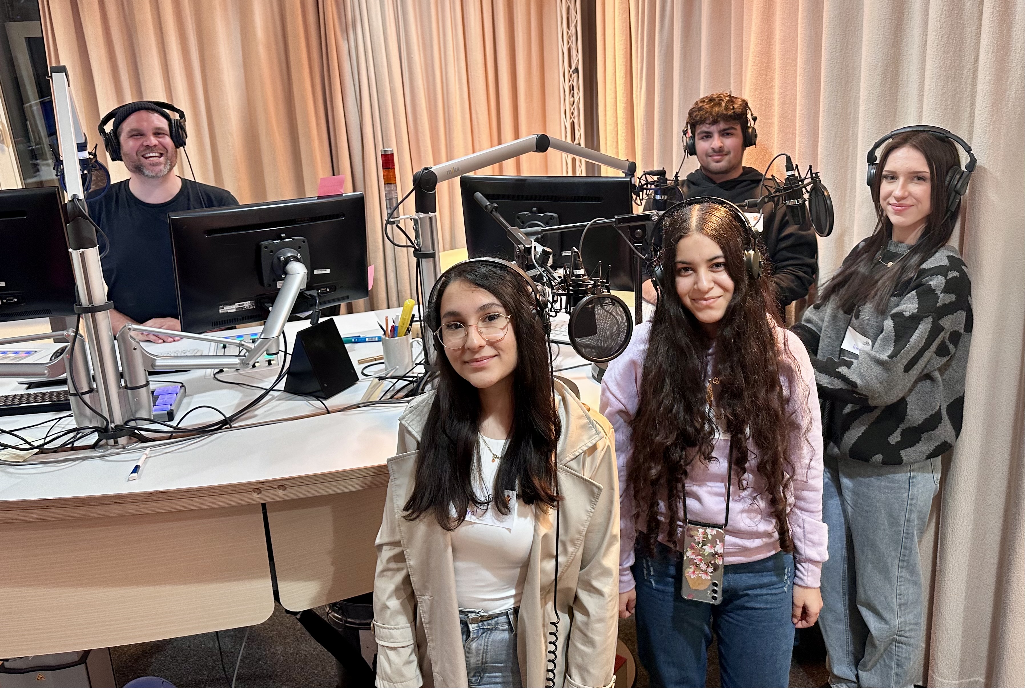 Vier Jugendliche und ein Moderator stehen in einem Radiostudio.